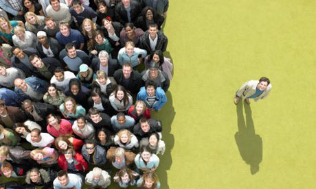 Young man standing to the side of a large crowd